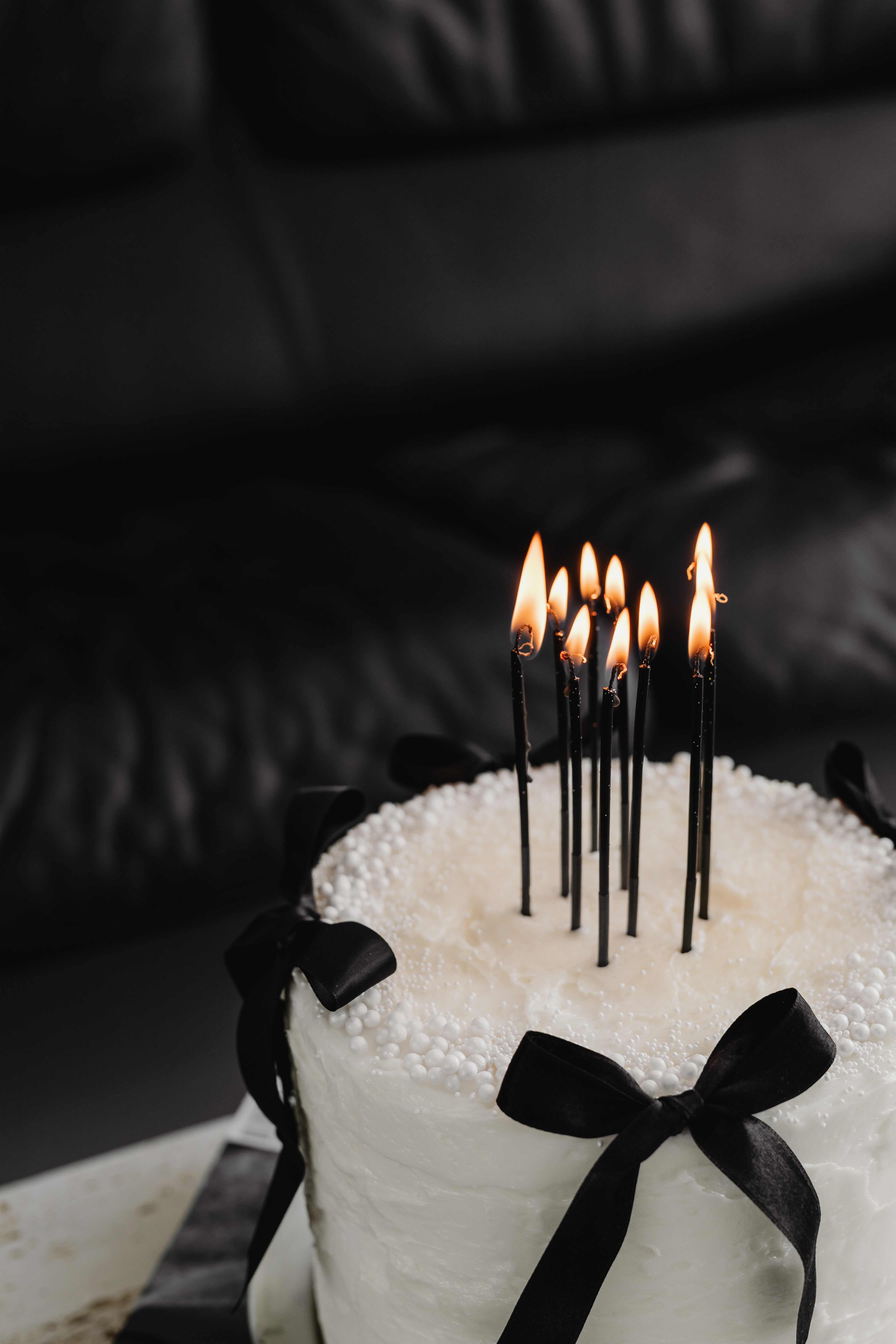 A birthday cake with black candles and a black bow
