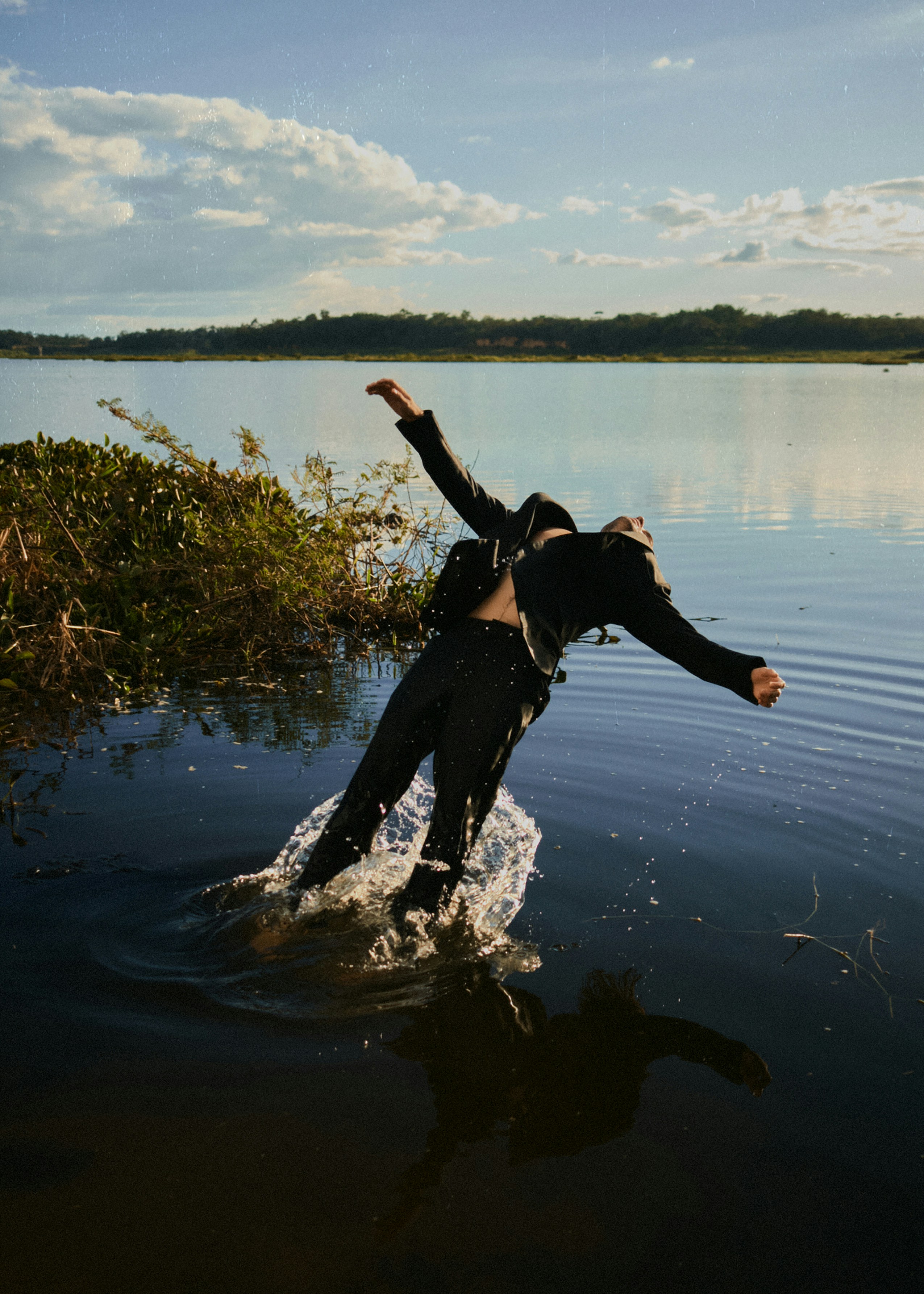 A figure diving into a lake, raw and unposed
